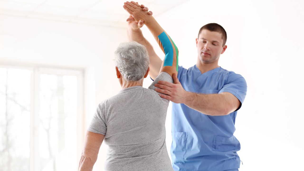 Kinésithérapeute réalisant une séance de kinésithérapie seniors au domicile du patient